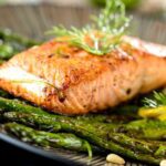 cooked and marinated salmon on plate with asparagus