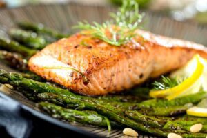 cooked and marinated salmon on plate with asparagus