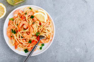 Seafood Pasta spaghetti with shrimps and parsley on gray stone background.