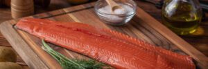 whole raw salmon fillet on wooden cutting board