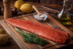 whole raw salmon fillet on wooden cutting board