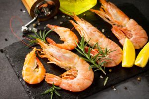 Raw shrimps with spice and lemon on a slate board.