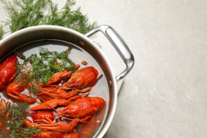 Fresh delicious crayfishes in pot on light grey table, flat lay. Space for text