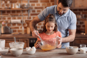'portrait of father and daughter cooking together in kitchen